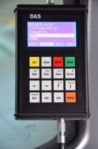 Urządzenie DAS z ekranem LCD wyświetlającym menu i klawiaturą numeryczną. Kluczowe obiekty: ekran, przyciski, złącze.