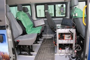 Wnętrze furgonetki z siedzeniami, laptopami i sprzętem elektronicznym.