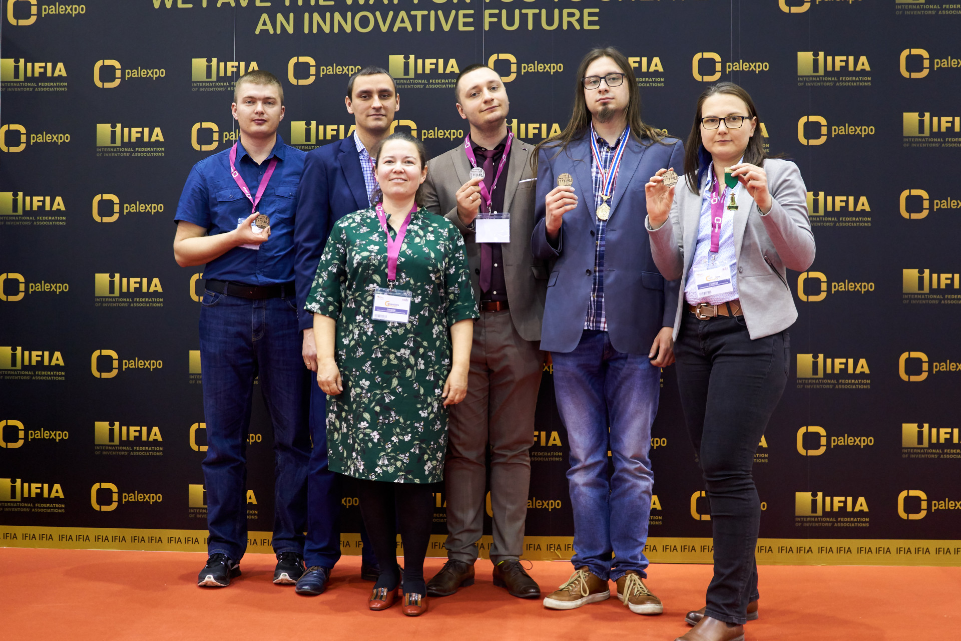 Osoby z medalami na tle logotypów IFIA i Palexpo. Kontekst: wydarzenie branżowe, wręczenie nagród.
