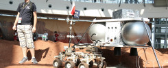 Robot marsjański z polską flagą. W tle ludzie i konstrukcja budynku.