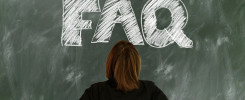 Osoba patrzy na tablicę z napisem "FAQ" napisanym kredą. Kontekst: edukacja, pytania i odpowiedzi.