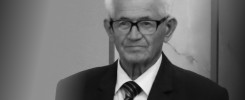 Czarno-białe zdjęcie starszego mężczyzny w okularach, garniturze i krawacie.